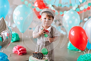 Adorable happy baby boy eating cake one at his first birthday cakesmash party