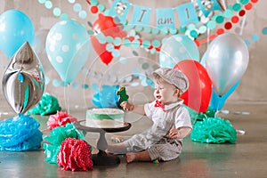 Adorable happy baby boy eating cake one at his first birthday cakesmash party
