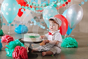 Adorable happy baby boy eating cake one at his first birthday cakesmash party