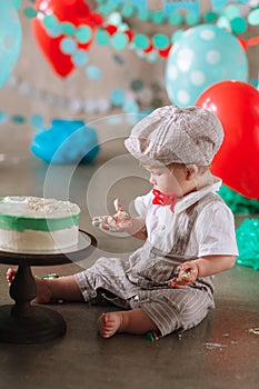 Adorable happy baby boy eating cake one at his first birthday cakesmash party