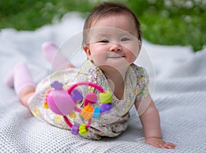 adorable and happy baby girl hat embraces the joys of playfulness on a soft blanket playing with little toy. Laughing as she