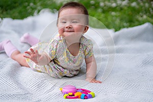 adorable and happy baby girl hat embraces the joys of playfulness on a soft blanket playing with little toy. Laughing as she