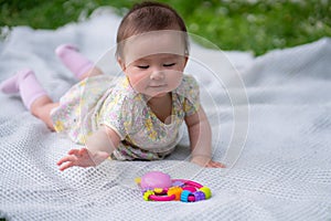 adorable and happy baby girl hat embraces the joys of playfulness on a soft blanket playing with little toy. Laughing as she