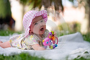 adorable and happy baby girl hat embraces the joys of playfulness on a soft blanket playing with little toy. Laughing as she