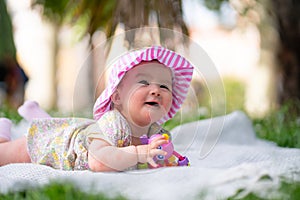 adorable and happy baby girl hat embraces the joys of playfulness on a soft blanket playing with little toy. Laughing as she