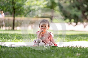 adorable and happy baby girl playing outdoors in the park - portrait of 7 or 8 months old beautiful little child smiling cheerful
