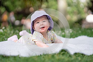 adorable and happy baby girl in summer hat embraces the joys of playfulness on a soft blanket. Laughing as she explores the