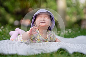 adorable and happy baby girl in summer hat embraces the joys of playfulness on a soft blanket. Laughing as she explores the