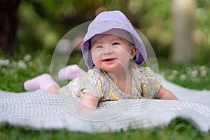 adorable and happy baby girl in summer hat embraces the joys of playfulness on a soft blanket. Laughing as she explores the