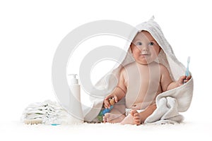 Adorable happy baby smiling under a white towel with teeth brush. Bath time.