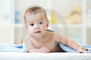 Adorable happy baby under towel indoor