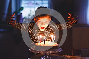 Adorable happy blond little kid boy celebrating his birthday. Child blowing candles on homemade baked cake, indoor