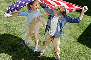 Adorable happy brother and sister waving american flag