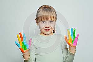 Adorable happy child girl art school student showing her colorful painted hands on white. Girl drawing