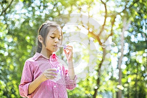 Adorable happy cute girl playful foam bubbles in green playground in summer outdoors. Funny Cheerful girl in the park happiness