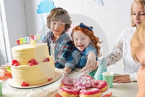 adorable happy kids eating delicious sweets at birthday