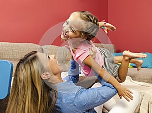 Adorable happy little girl flying throw air in her mothers arms