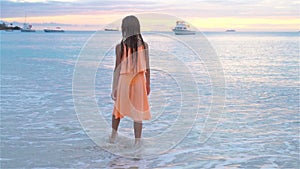 Adorable happy little girl walking on white beach at sunset. SLOW MOTION