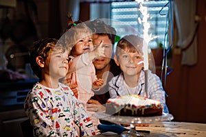 Adorable happy little kid boy celebrating his birthday. Child blowing candles on cake. Father, brother and baby sister