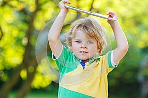 Adorable happy little kid boy holding tablet pc, outdoors