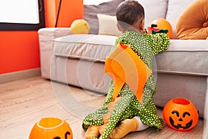 Adorable hispanic boy wearing dragoon costume playing with tractor at bedroom