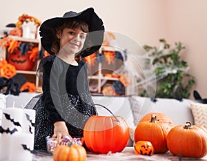 Adorable hispanic girl having halloween party holding sweet of bowl at home