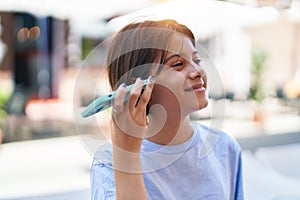 Adorable hispanic girl miling confident listening audio message by the smartphone at street