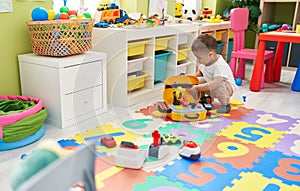 Adorable hispanic toddler playing with tools toys at kindergarten