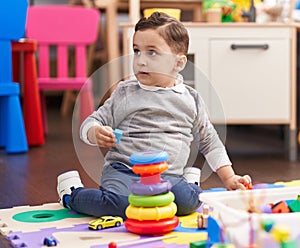Adorable hispanic toddler playing with toys sitting on floor at kindergarten