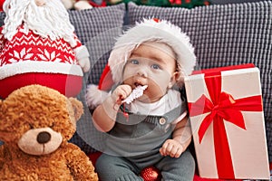 Adorable hispanic toddler wearing christmas hat bitting star decoration at home