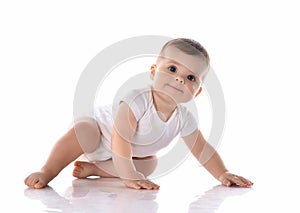 Adorable infant baby in diaper and white bodysuit is crawling on all fours looking at camera, going to stand up. Side view