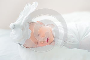 Adorable infant girl in white pajama sleeping on white cloth mattress. newborn baby having day nap in parent`s bed