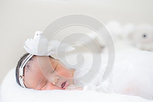 Adorable infant girl in white pajama sleeping on white cloth mattress. newborn baby having day nap in parents`s bed