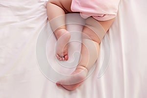 Adorable innocent baby try to crawling on bed that the first time infant baby crawl. Lovely toddler girl wear pink baby dress.