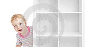 Adorable kid boy behind empty white shelves