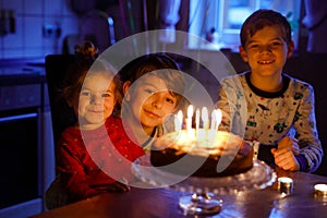 Adorable kid boy celebrating tenth birthday. Baby sister child and two kids boys brothers blowing together candles on