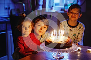 Adorable kid boy celebrating tenth birthday. Baby sister child and two kids boys brothers blowing together candles on