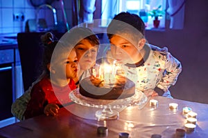 Adorable kid boy celebrating tenth birthday. Baby sister child and two kids boys brothers blowing together candles on