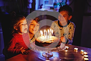 Adorable kid boy celebrating tenth birthday. Baby sister child and two kids boys brothers blowing together candles on