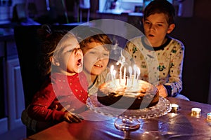 Adorable kid boy celebrating tenth birthday. Baby sister child and two kids boys brothers blowing together candles on