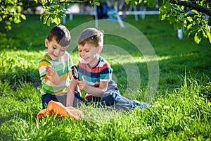 Adorable kid boy making fire on paper with a magnifying glass outdoors, on sunny day