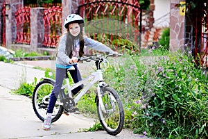 Adorable kid girl in blue helmet riding her bike