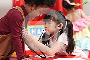 Adorable kid pretending to be doctor, playing funny and holding doctor stethoscope, pretending nurse treating friend as patient