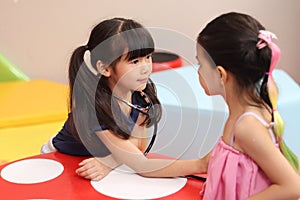 Adorable kid pretending to be doctor, playing funny and holding doctor stethoscope, pretending nurse treating friend as patient