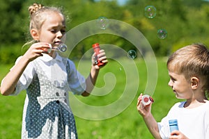 Adorable kids blow bubbles outdoors