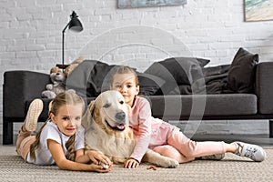 adorable kids hugging golden retriever dog while sitting on floor