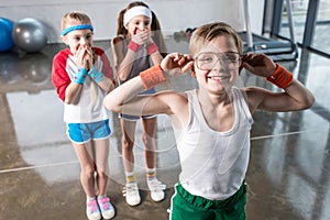 Adorable kids in sportswear fooling around at fitness studio