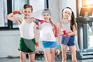 Adorable kids in sportswear smiling and posing at fitness studio