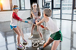 Adorable kids in sportswear training with ropes at fitness studio