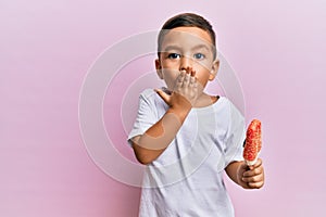 Adorable latin toddler holding ice cream covering mouth with hand, shocked and afraid for mistake